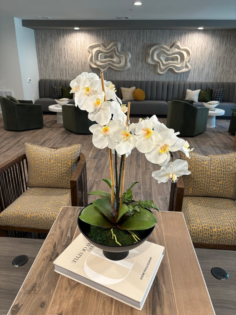 White orchid arrangement styled on coffee table books in a resident lounge