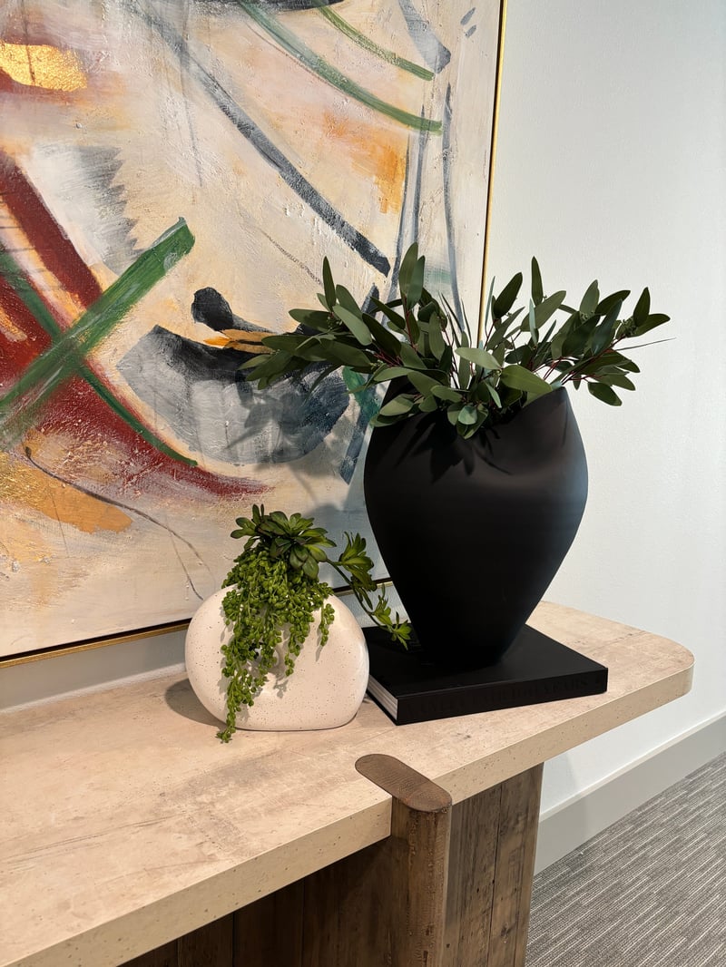 Olive branch arrangement in a black ceramic vase on a console table
