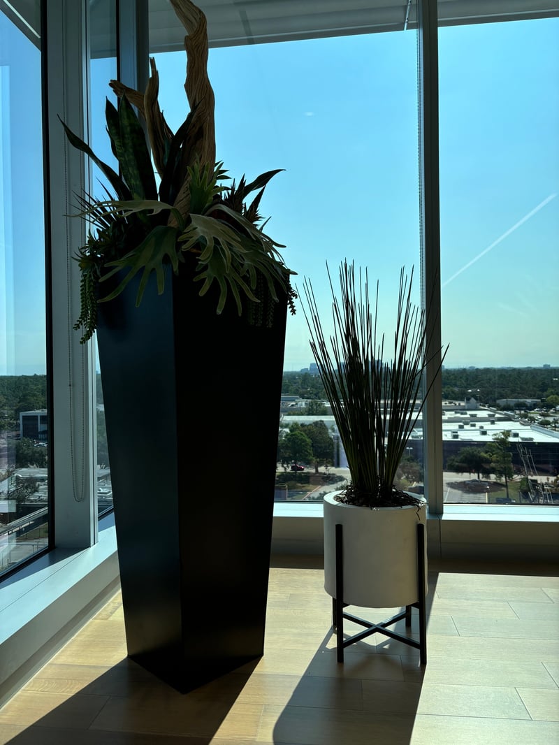 Sculptural floor planters at a floor-to-ceiling window, high above a city skyline